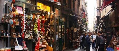 A narrow street with shops on both sides, displaying various items for sale.