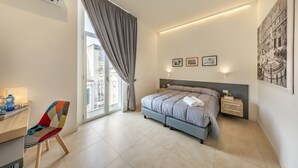 A modern bedroom with a bed, bedside tables, a desk, and a chair. - Napoli Squares Suites (Naples)