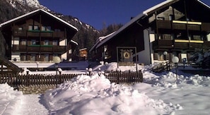 A snow-covered outdoor area with wooden buildings, a stone wall, and a sign that reads "Burgus Sol."
