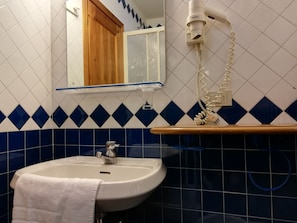 A bathroom with a sink, mirror, and a towel hanging on the wall.