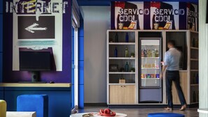 A modern interior with a computer setup, a beverage fridge, and colorful seating.