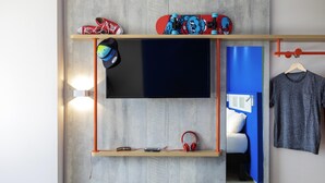 A modern room with a mounted TV, a shelf with a skateboard, a helmet, and headphones.