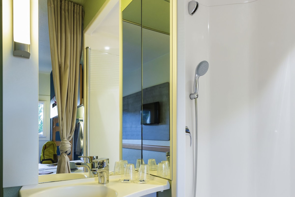 Ein modernes Badezimmer mit einem großen Spiegel, einem Waschbecken und einer Dusche.