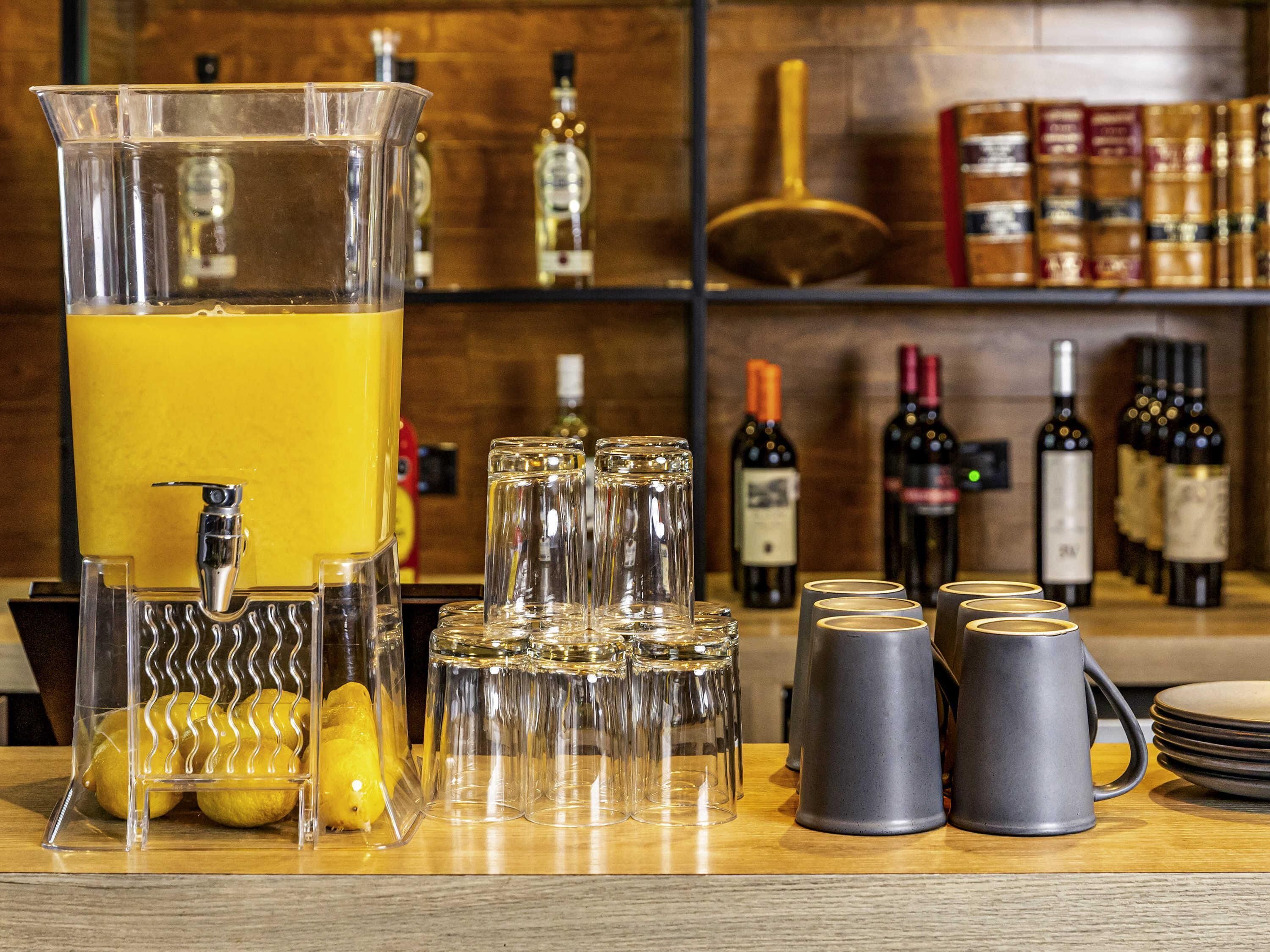 A bar area with a large pitcher, glasses, lemons, and bottles of alcohol.