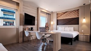 A modern hotel room with a wooden desk, a laptop, and a bed with white linens. - ibis Torreon (Torreón)