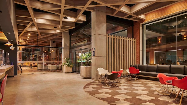 A modern interior with a wooden ceiling, seating area, and a reception desk. - ibis Torreon (Torreón)
