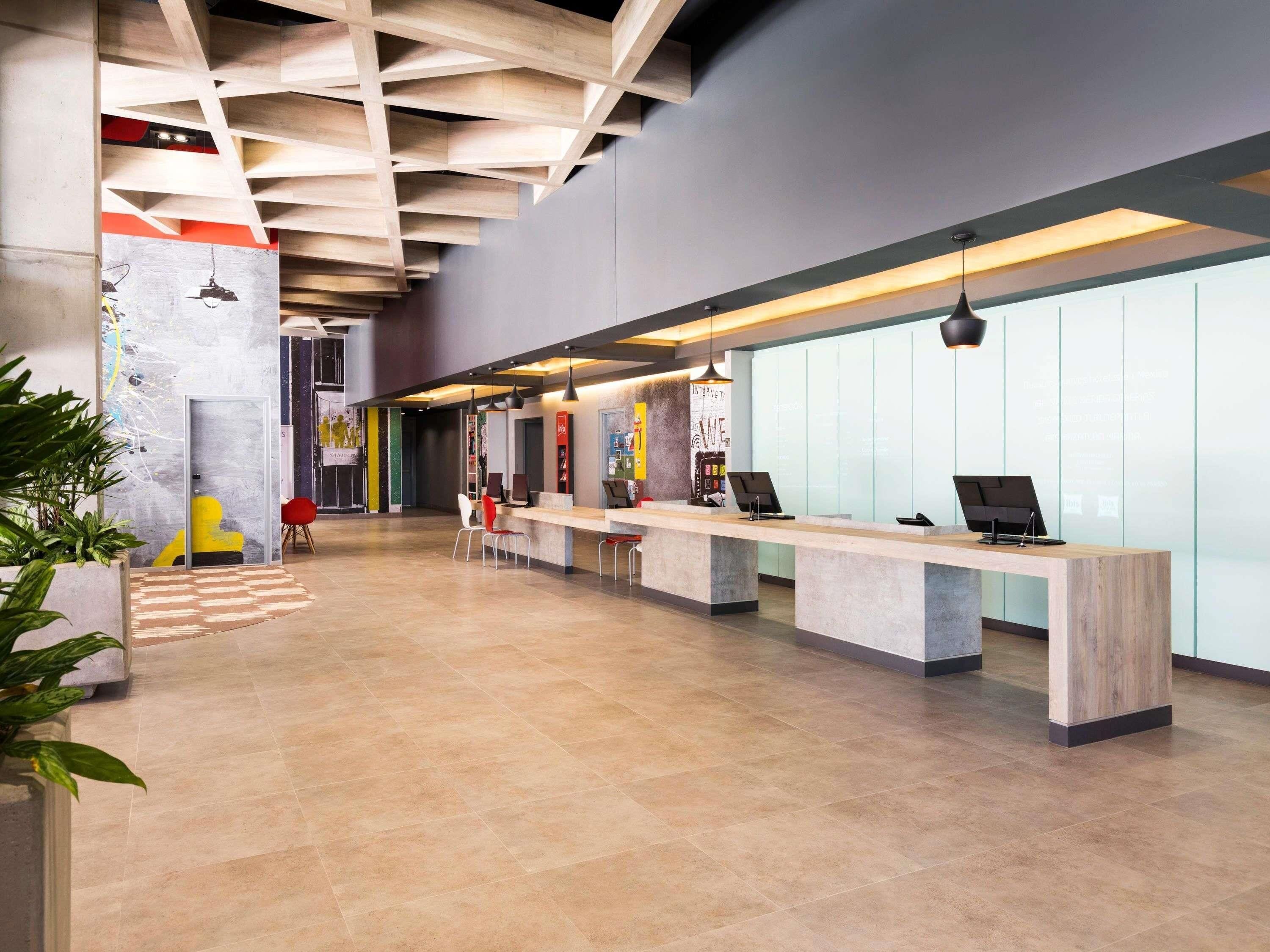 A modern reception area with a long reception desk, multiple chairs, and a high ceiling with exposed beams.