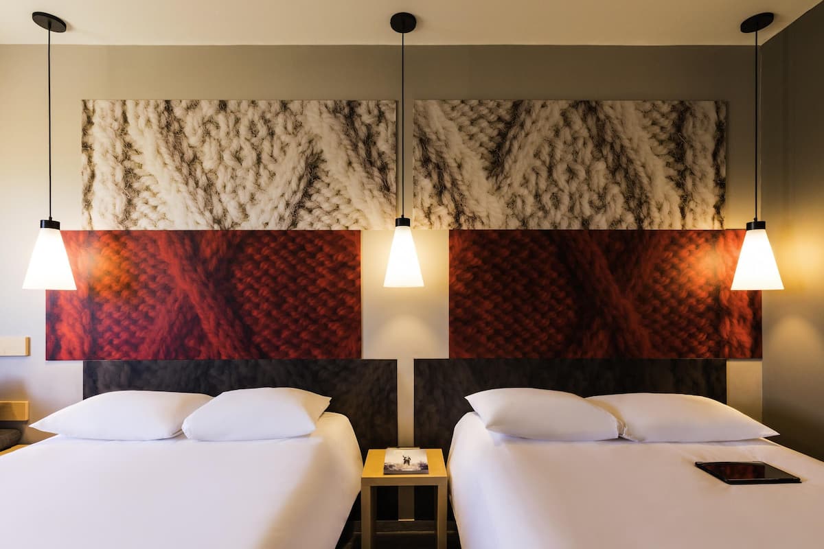 A hotel room with two beds, a nightstand, and a wall with a textured pattern.