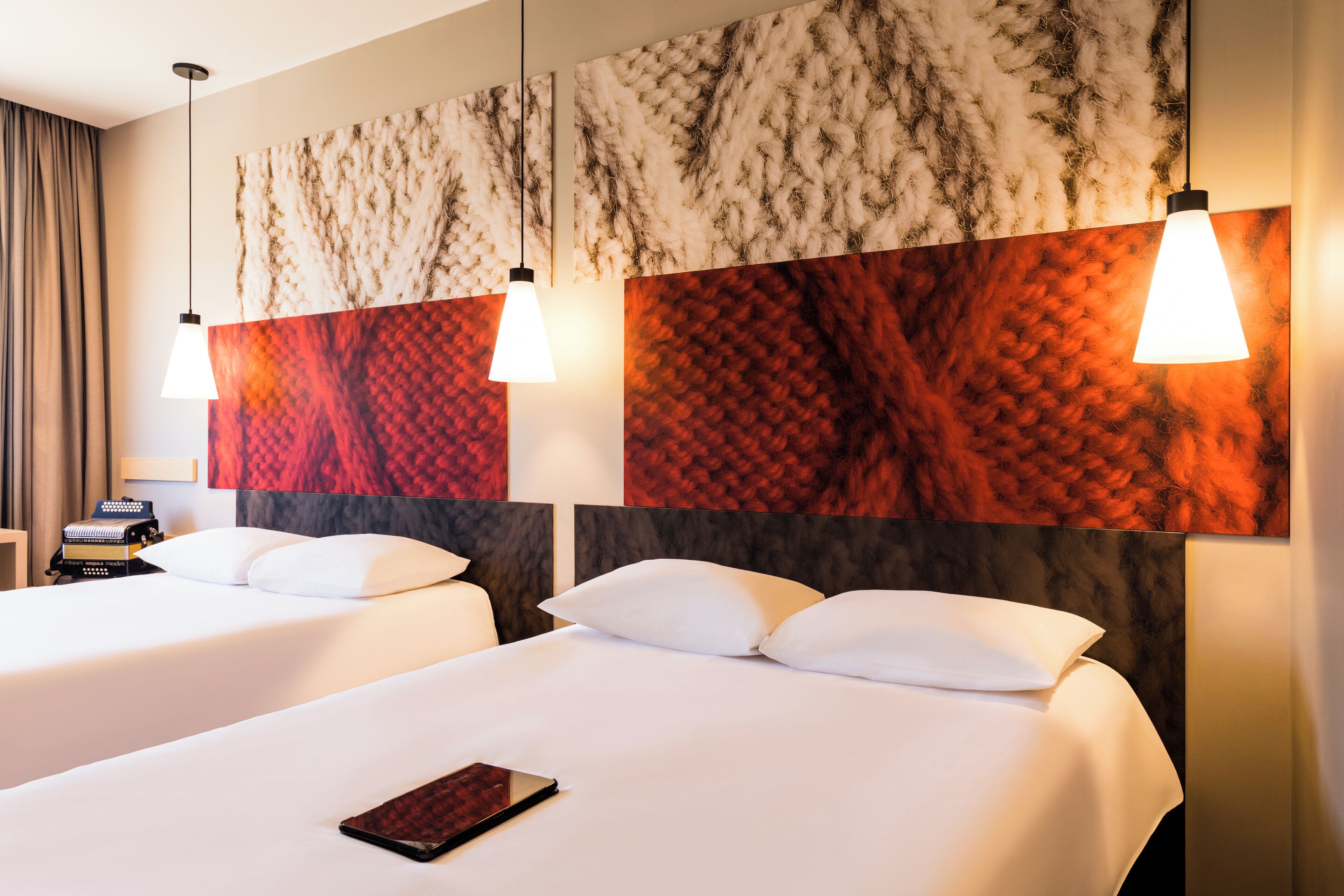 Habitación de hotel con dos camas, un cuadro abstracto grande en la pared y un escritorio con lámpara.