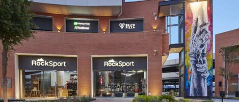 Un edificio con varias fachadas, incluyendo 'Enterprise National', 'BKLYN PIZZA' y 'RockSport'.