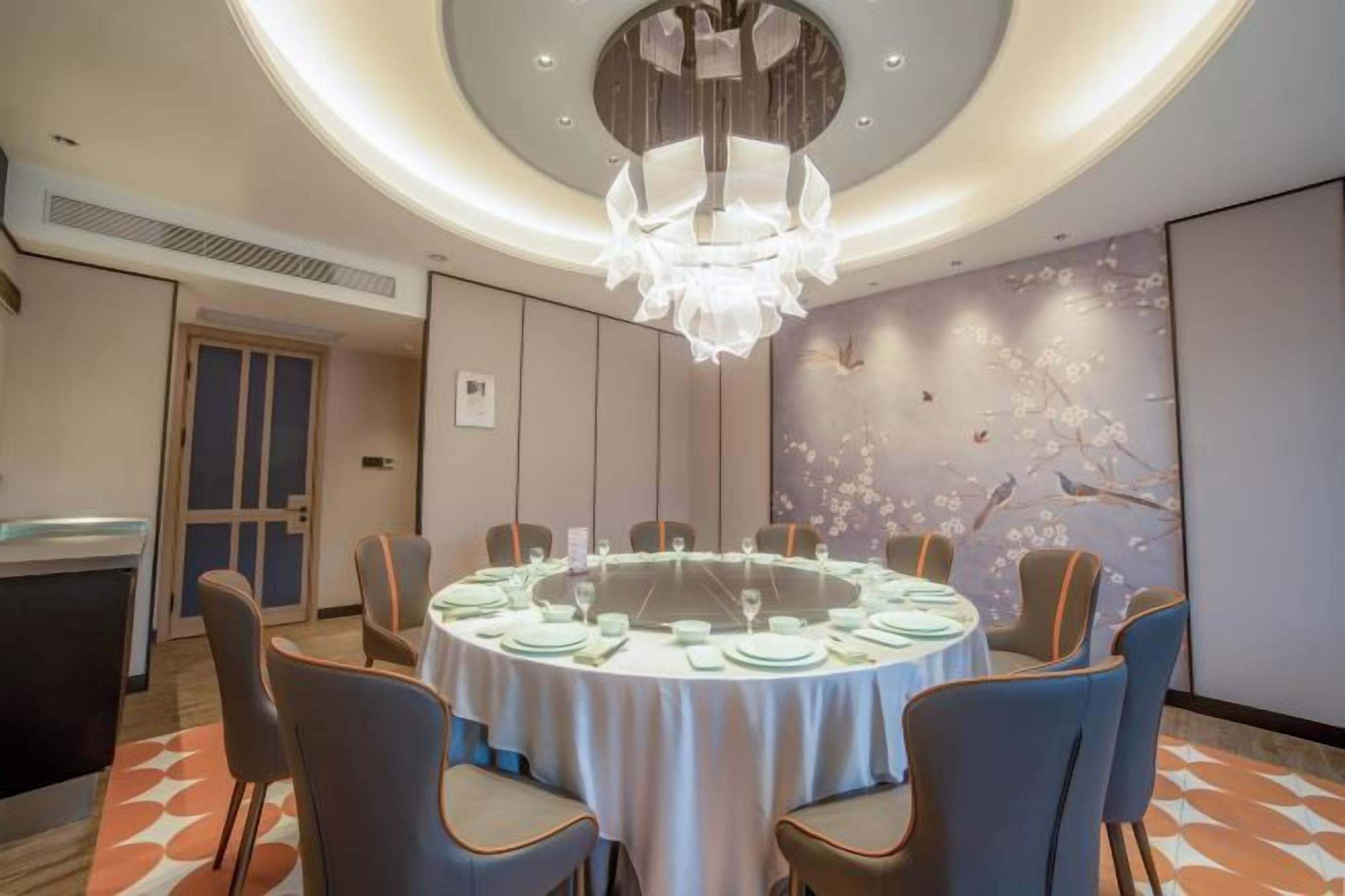 A conference room with a round table, chairs, and a chandelier.