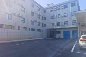 A multi-story building with a parking lot in front. - Zhoucun Shaobing Hotel (Zibo)