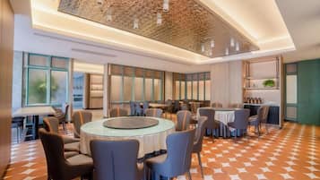 A modern hotel conference room with round tables, chairs, and a patterned floor.