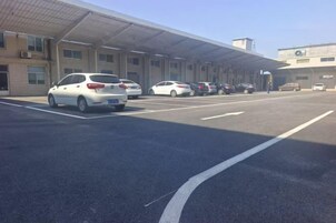 Un estacionamiento con varios autos y un edificio de techo plano y amplias ventanas.