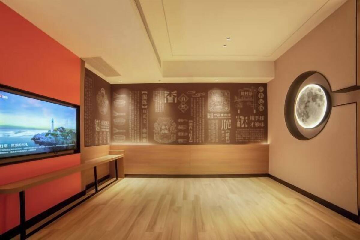 Ein Hotelzimmer mit einem großen Flachbildfernseher, einer Holzbänkl und einer Wand mit Dekor.