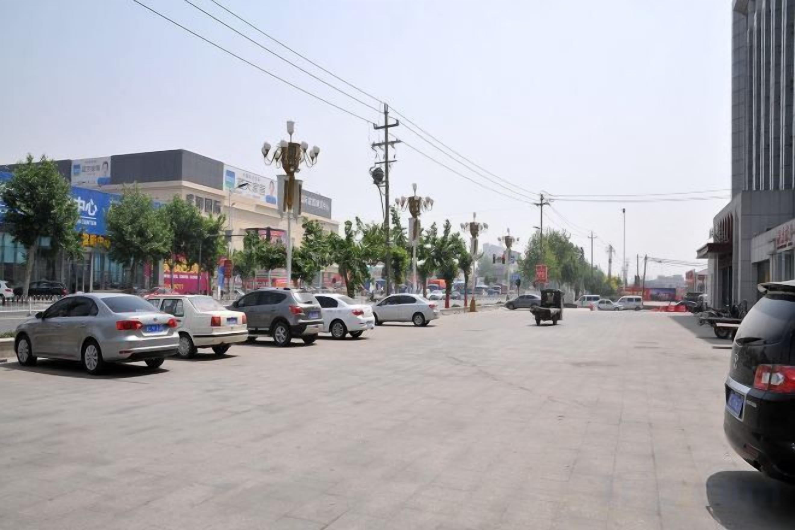 A parking lot with multiple cars, a clear sky, and buildings in the background.