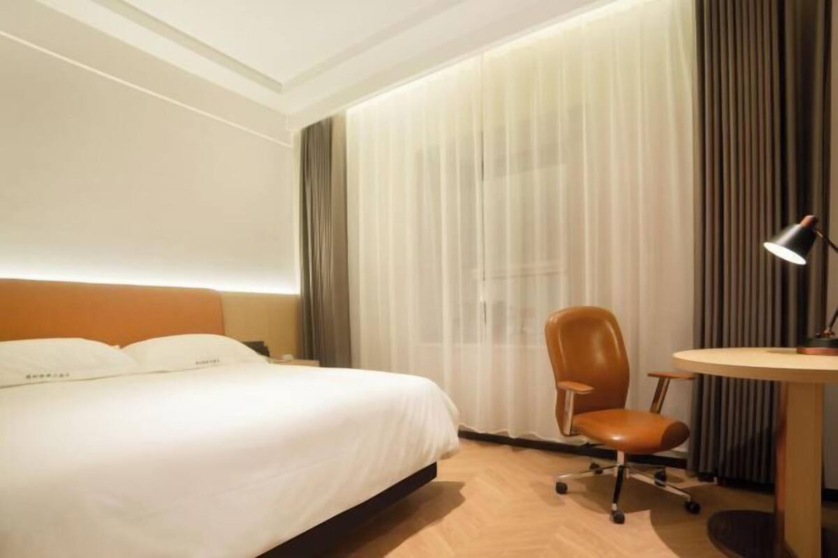 Ein Hotelzimmer mit einem Bett, einem Schreibtisch, einem Stuhl und einer Lampe.