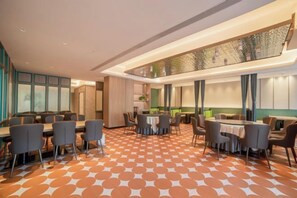 A hotel dining area with multiple tables and chairs, a patterned floor, and a high ceiling with recessed lighting. - Zhoucun Shaobing Hotel (Zibo)