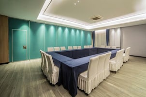 Una sala de conferencias con una larga mesa, sillas blancas, paredes color turquesa y suelo de madera.