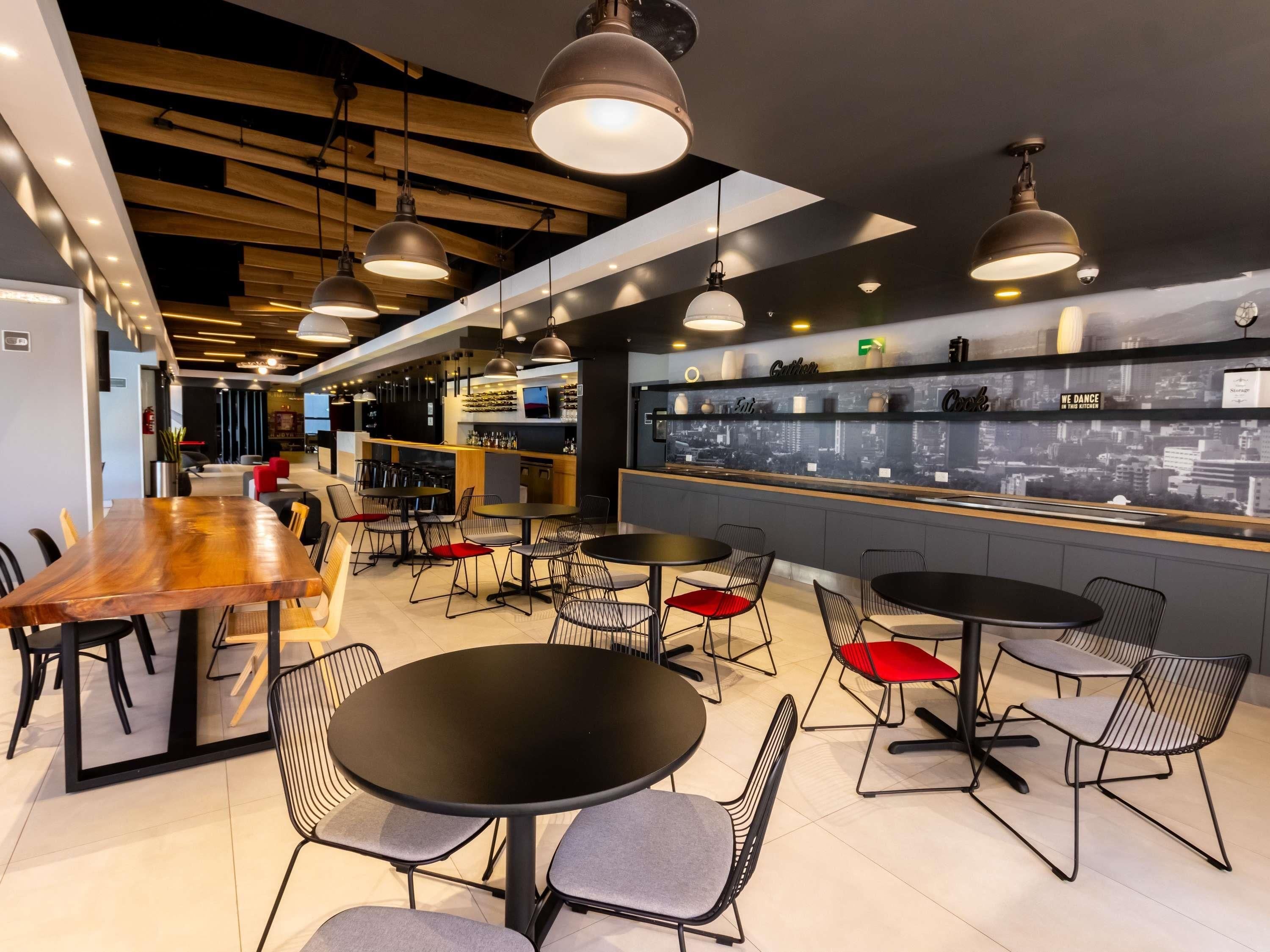 A modern bar area with multiple seating options, a bar counter, and a cityscape view.