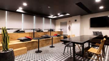 Un salón de conferencias con piso a cuadros blanco y negro, bancos de madera y una gran mesa con sillas.