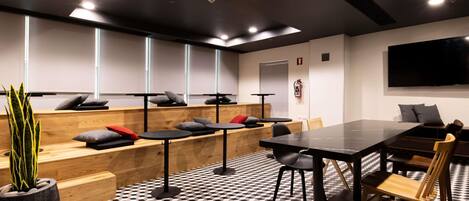 Un salón de conferencias con piso a cuadros blanco y negro, bancos de madera y una gran mesa con sillas.
