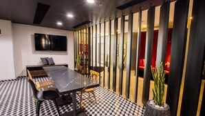 A modern meeting room with a large table, chairs, a TV, and a patterned floor.