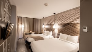 Une chambre d’hôtel avec deux lits, une télévision, un bureau et une tête de lit à motifs.