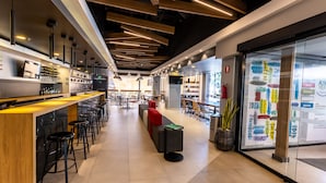 Un espace bar moderne avec des tabourets hauts, un long comptoir et un coin salon agrémenté d’un canapé rouge.