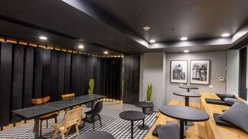 A modern conference room with a long table, chairs, and round tables.