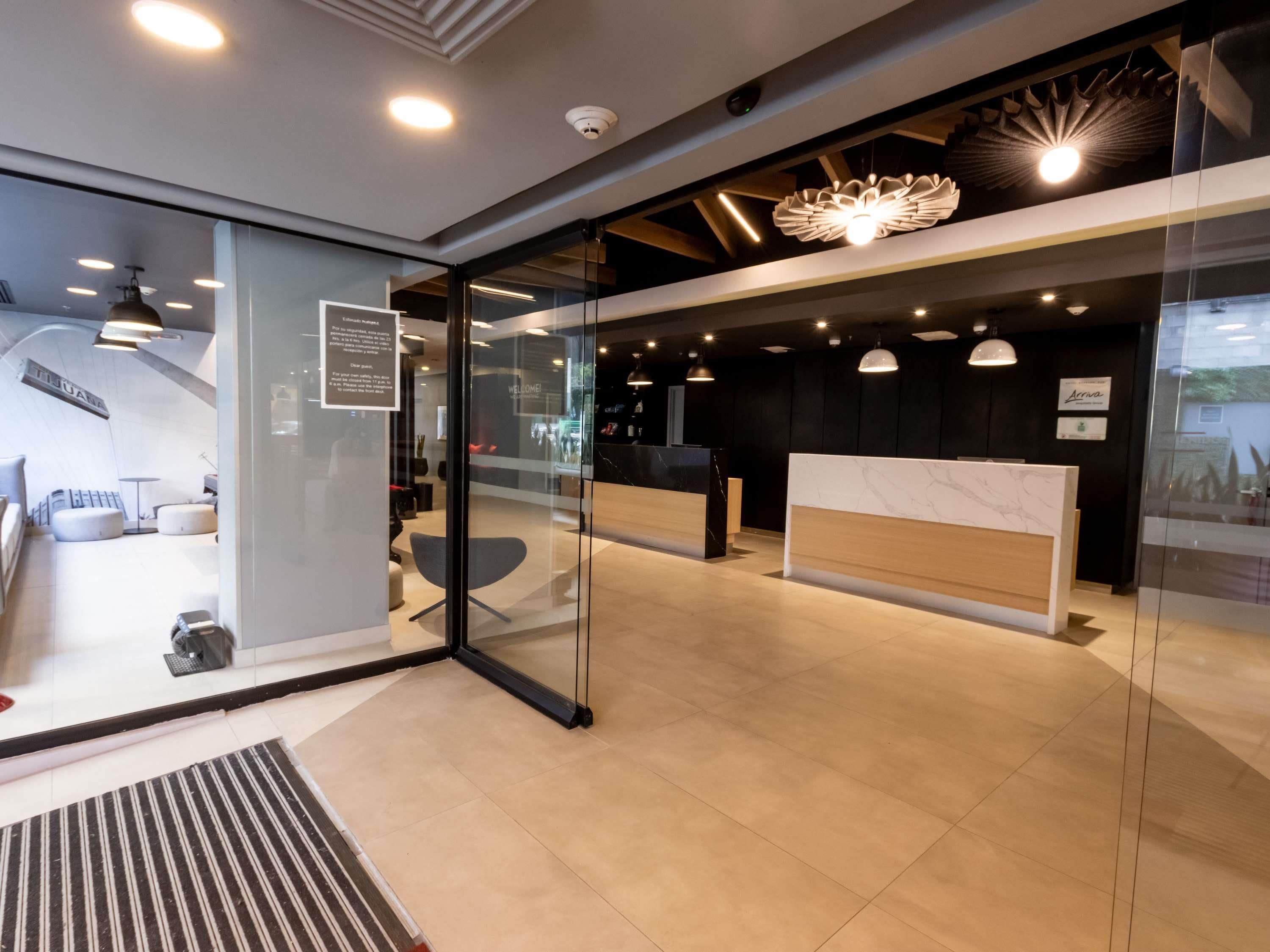 Una moderna zona de recepción con separadores de vidrio, mostrador de recepción y un área de estar con sofá y sillones.