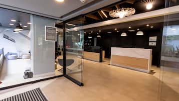 Una moderna zona de recepción con separadores de vidrio, mostrador de recepción y un área de estar con sofá y sillones.