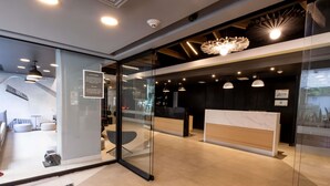Un espace d’accueil moderne doté de cloisons en verre, d’un comptoir de réception et d’un coin salon avec un canapé et des fauteuils.