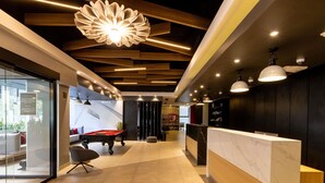 A modern indoor space with a pool table, a reception desk, and a lounge area with seating.