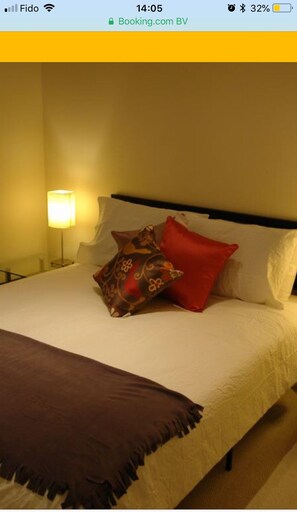 Une chambre d’hôtel avec un lit, des oreillers et une table de chevet avec une lampe.