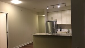 Una cocina compacta con armarios blancos, un refrigerador de acero inoxidable y una pequeña encimera.