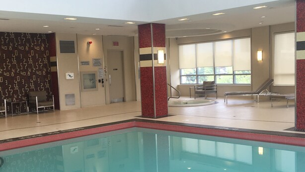 Una piscina interior con agua cristalina, rodeada de sillones de descanso y una pared de azulejos con diseño geométrico.