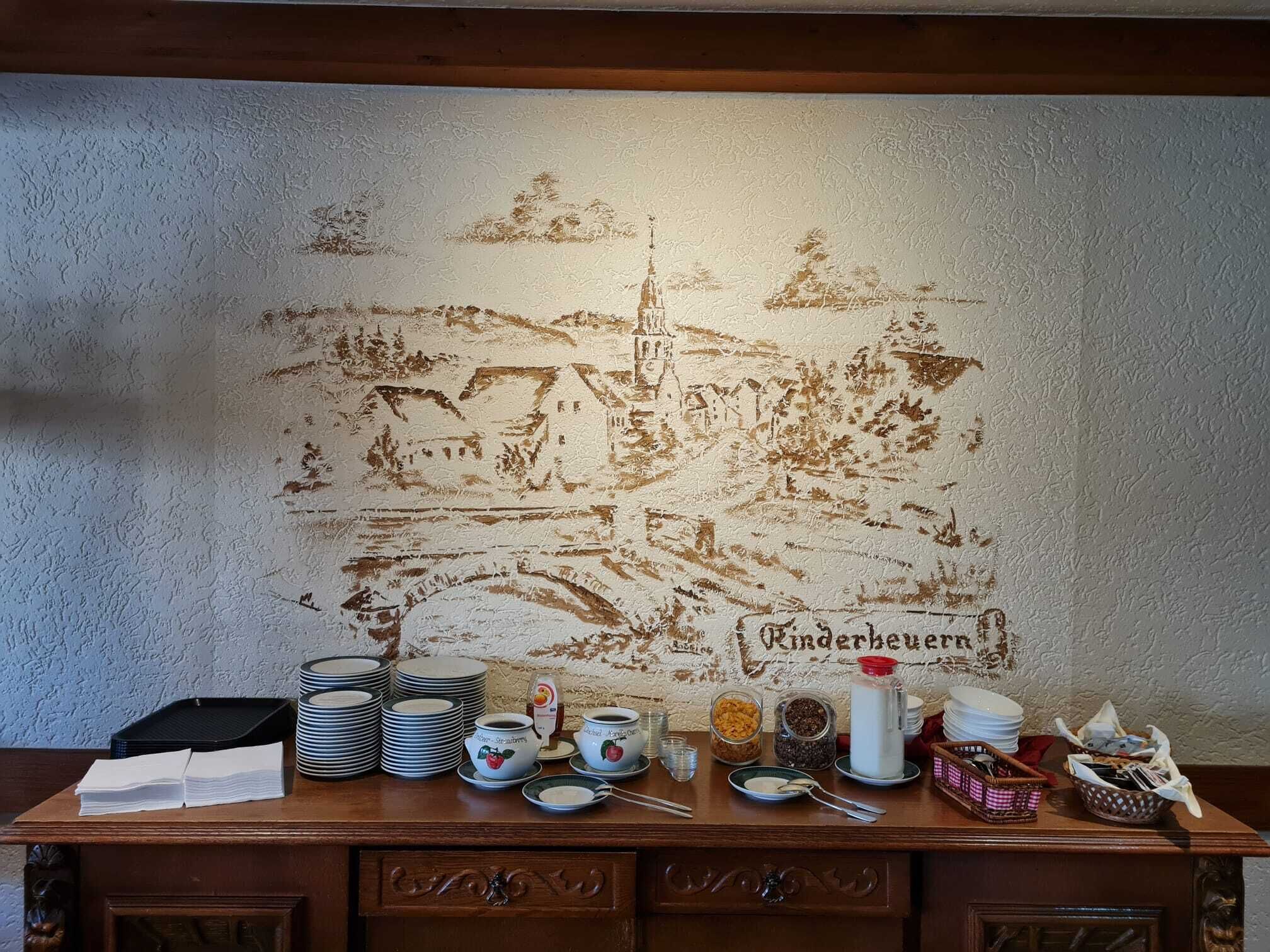 Ein Tisch mit gestapelten Tellern, Schüsseln und einem Gemälde einer Stadtansicht.
