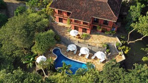 A large building with a swimming pool, surrounded by lush greenery and outdoor seating areas. - Hacienda Barrigona (Sámara)