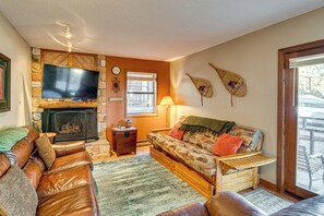 A cozy living room with a fireplace, leather sofa, television, and a window with a view. - Cozy Angel Fire Condo < Half Mi to Resort! (Angel Fire)