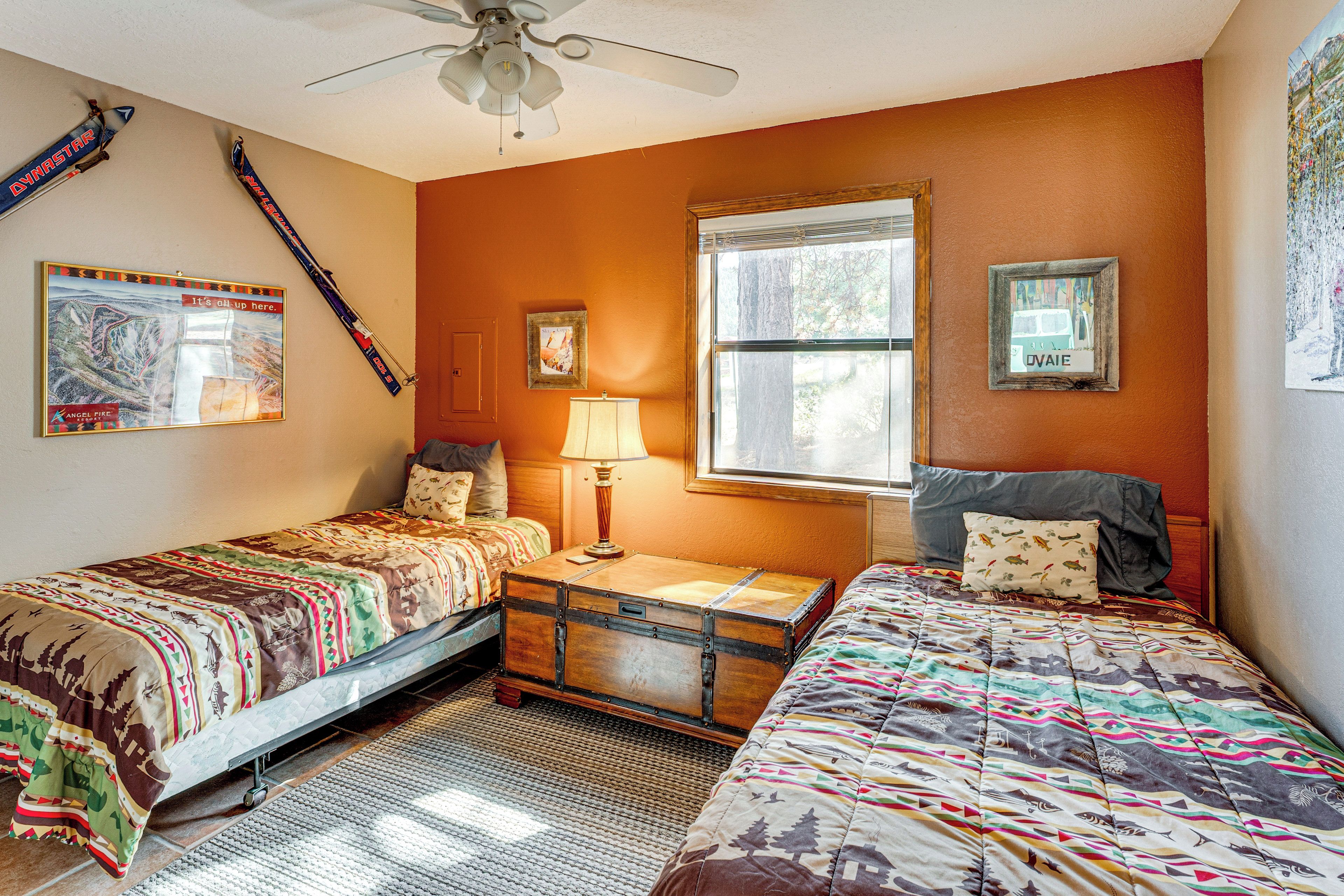 A bedroom with two beds, a window, a ceiling fan, and wall decorations.