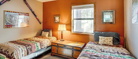 A bedroom with two beds, a window, a ceiling fan, and wall decorations.