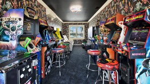 Una stanza con cabinati arcade, sgabelli da bar e una finestra con vista.