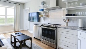 Una cucina moderna con mobili bianchi, elettrodomestici in acciaio inossidabile e un televisore a schermo piatto montato sopra il forno.