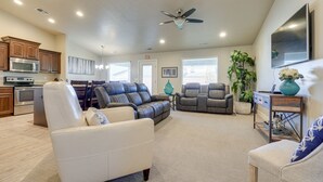 A spacious living room with a sofa, chairs, a coffee table, and a TV. There is a kitchen area with cabinets and appliances. - Private Pool, Mtn Views! Hurricane Group Getaway (Hurricane)