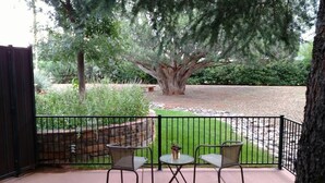 Une terrasse extérieure avec deux chaises en métal et une petite table ronde, le tout entouré d’une clôture en métal noir.