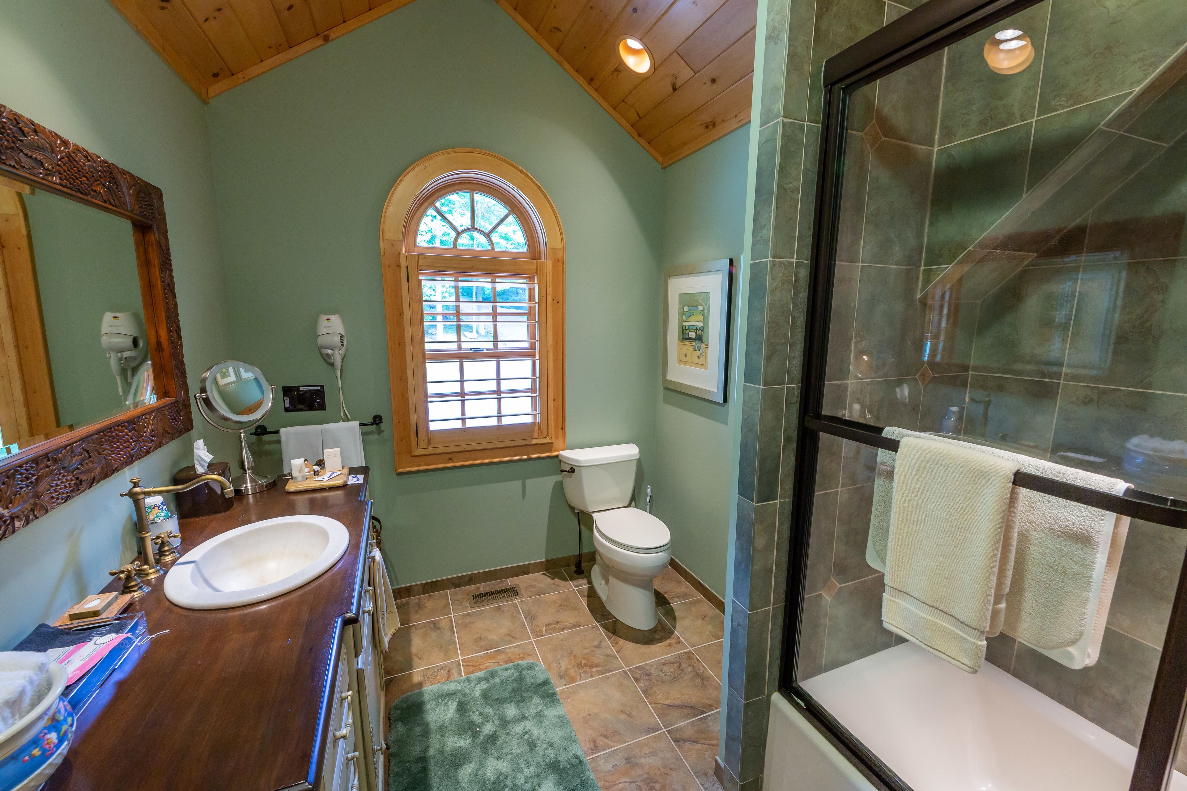 Une salle de bain avec un meuble-lavabo en bois, un lavabo, des toilettes et un espace douche.