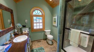 Une salle de bain avec un meuble-lavabo en bois, un lavabo, des toilettes et un espace douche.