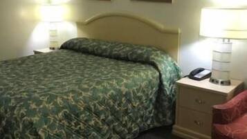 A hotel room with a bed, two bedside lamps, a nightstand with a phone, and two framed pictures on the wall.