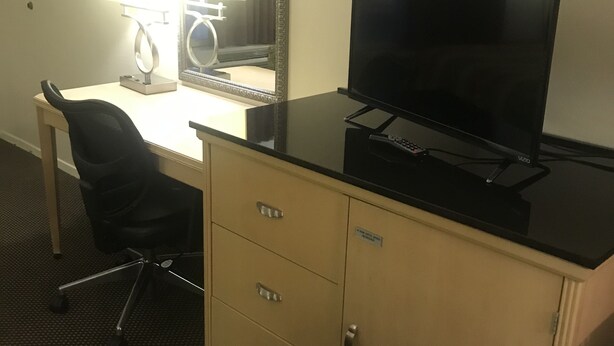 Ein Hotelzimmer mit Schreibtisch, Stuhl, Fernseher und Schrank.